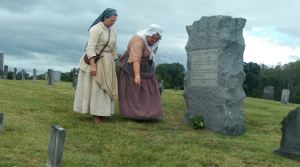 Pam Eddy and Lisa Bennett pouring black powder of Mary Patton's grave